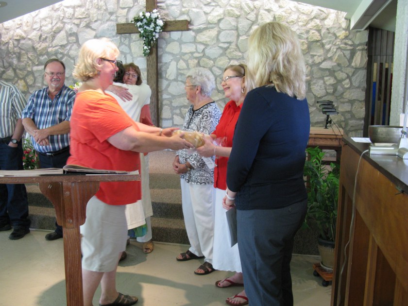 Advisor, Denise Williams, and Rev. Wells give new member, Patti Cooksey, a gift of newly baked bread and extend the right hand of friendship